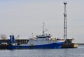 Old rusty blue and white fishing trawler, starboard and big grey concrete breakwater in the background