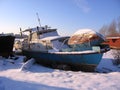 Old rusty boat moored to the shore in the winter froze on the river