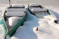 Old rusty boats covered with snow on the banks of a frozen river on a sunny day. Royalty Free Stock Photo