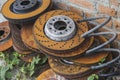 Old rusty brake discs lie in the grass near a brick wall Royalty Free Stock Photo