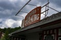 Old, rusty, broken store signage in an abandoned shop. Stormy clouds in the background