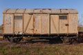 Old rusty brown train wagon on abandoned tracks