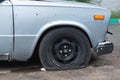 An old rusty car with a punctured front wheel