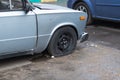 An old rusty car with a punctured front wheel