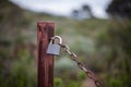 Old and rusty chain with a closed padlock in the field Royalty Free Stock Photo