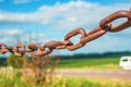 Old rusty chain on the field on the background of the sky Royalty Free Stock Photo