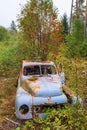 Old rusty classic car in a forest at autumn