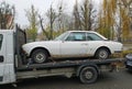 Old rusty classic white Peugeot 504 coupe on a trailer