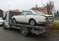 Old rusty classic white Peugeot 504 coupe on a trailer