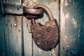 Old rusty closed lock without key. Vintage wooden door, close up concept photo