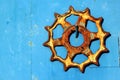 Old rusty cogwheel hanging on blue metal wall background