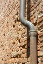 Old rusty copper and cast iron downpipe against a brick wall Royalty Free Stock Photo