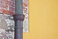 Old rusty copper and cast iron downpipe against a brick and yellow plaster wall - image with copy space