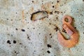 Old rusty crane hook on a dirty burnt tarpaulin canvas close-up