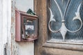 Old rusty dented mailbox at a house entrance with old door and iron fittings at a house in need of renovation and abandoned, Germa