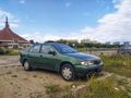 Old, rusty, dented scrap green car Nissan Almera four doors sedan parked Royalty Free Stock Photo