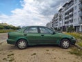 Old, rusty, dented scrap green car Nissan Almera four doors sedan parked Royalty Free Stock Photo