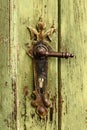 Old rusty door handle on green door. Detail of rustic old vintage and rusty grungy iron door handle installed on an ornament door Royalty Free Stock Photo