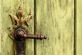 Old rusty door handle on green door. Detail of rustic old vintage and rusty grungy iron door handle installed on an ornamented old Royalty Free Stock Photo