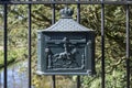 An old, rusty dutch mailbox hangs on a fench Royalty Free Stock Photo