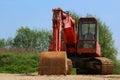 Old rusty excavator with broken window on sandy ground