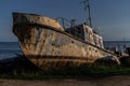old rusty fishing boat, ship on grassy shore of lake Baikal, sea in light of sunset Royalty Free Stock Photo