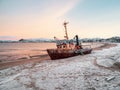 An old rusty fishing boat washed up on a sandy beach in the Barents Sea Royalty Free Stock Photo