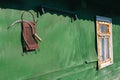 Old rusty grater and sickle on a green wooden wall of a house with a white retro window