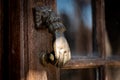 Old rusty and grungy hand shaped golden door knocker on a wooden door with tiny windows Royalty Free Stock Photo