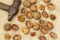 Old rusty hammer and cracked walnuts. Shells, nut kernels and whole nuts on crumpled paper Royalty Free Stock Photo