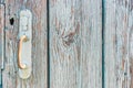 Old rusty handle on wooden door with cracked peeling blue paint close up. Texture of weathered painted wood with copy space for Royalty Free Stock Photo