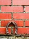 Old rusty horse shoe on a red color brick wall. Symbol on luck in a country setting. Rural theme Royalty Free Stock Photo