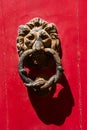Old rusty iron lion head door knocker on a red door Royalty Free Stock Photo