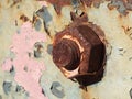 Rusty nut on iron with aged paint of different colors and rust