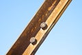 Old rusty iron structure with bolted metal profiles against a blue sky