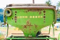 Old, rusty John Deere tractor seat, showing the word mark logo on the back, worn out. Classic John Deere image of an antiquated