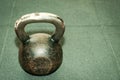 Old rusty kettlebell weight on the black gym floor with selective focus and film grain.