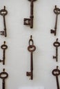 Old rusty keys hanging on a white wall.