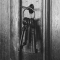 Old rusty keys inside a keyhole of an old antique closet. vintage design black and white Royalty Free Stock Photo