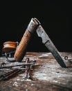 Isolated old pocket knife sticking in a wooden plate with rusty nails in foreground Royalty Free Stock Photo