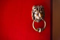 Old rusty lion door knocker on bright red painted door. Royalty Free Stock Photo