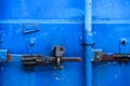 Old rusty lock on the bright blue door of a metal sea container, close-up Royalty Free Stock Photo