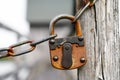 Old rusty lock hanging on the chain. Vintage old padlock. Sturdy lock to hold a chain together