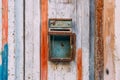 Old rusty mailbox on colour wooden door close up. Peeling paint door. Vintage rusty postbox or letterbox concept.