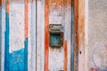 Old rusty mailbox on colour wooden door. Peeling paint door. Vintage rusty postbox or letterbox concept. Copy space.