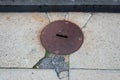 Old rusty manhole cover in concrete and asphalt sidewalk, copy space Royalty Free Stock Photo