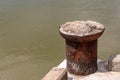 Old rusty metal bollard mooring boats on the background of a muddy river