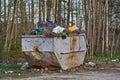 An old rusty metal container overflowing with rubbish.