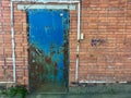 Old rusty metal door. Old brick wall. Bad living conditions