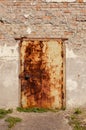 An old rusty metal door in a stone wall. The front door is locke Royalty Free Stock Photo